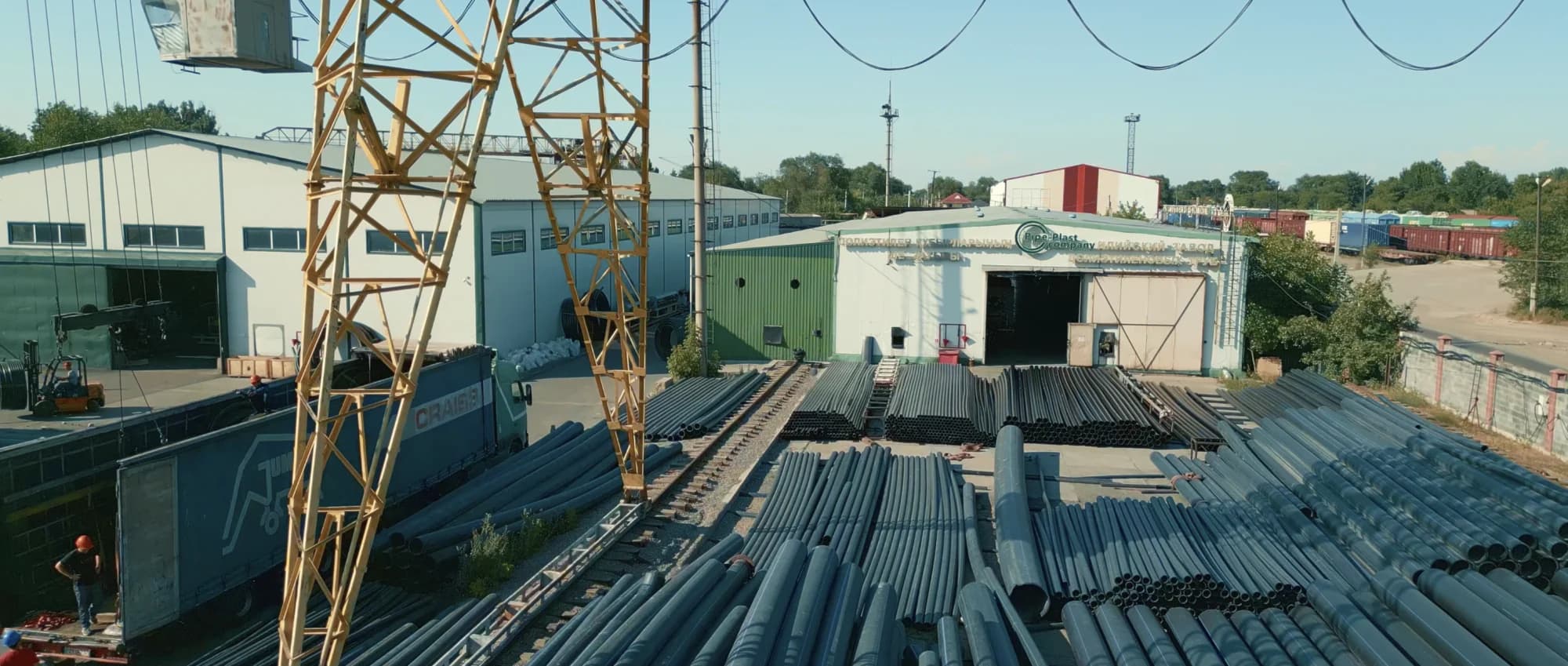 Склад готовых полиэтиленовых труб на территории завода Pipe-Plast: штабели чёрных труб и производственные корпуса
